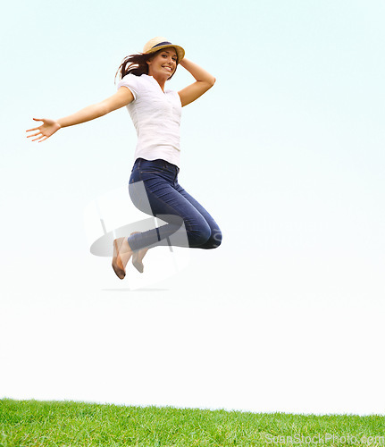 Image of Nature, happy and woman jumping on grass for positive, joyful and confident attitude by blue sky. Smile, portrait and young female person from Canada leap on green lawn at outdoor garden in summer.