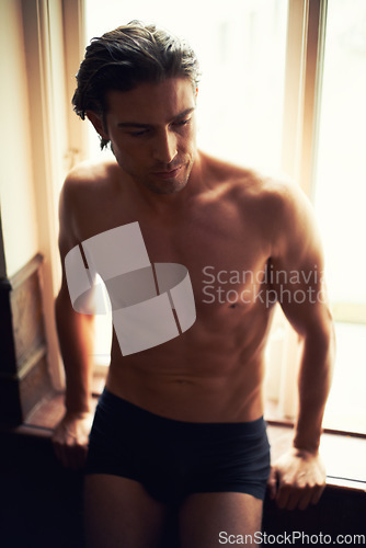 Image of Underwear, thinking or man in home by window for bodybuilding workout, training or exercise. Shirtless model, healthy bodybuilder or topless person with shadow, six pack or body muscle for fitness