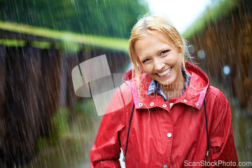 Image of Woman, smile and raincoat in outdoor storm, wet and cold from weather, winter and nature. Happy female person, fashion and red jacket is cool, rainfall and protection from water, face and travelling