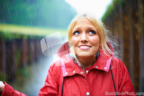 Image of Woman, smile and raincoat for rain in nature, wet and cold from weather, winter and outdoor. Happy female person, fashion and red jacket is cool, rainfall and protection from water, face and vacation