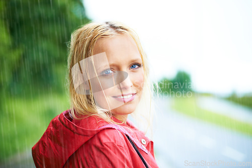 Image of Happy, portrait and young woman in the rain with coat in nature, road or street for winter. Smile, positive attitude and female person from Australia in drizzle or storm weather in outdoor forest.