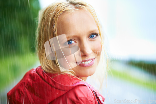 Image of Happy, smile and young woman in the rain with coat in nature, road or street for winter. Portrait, positive attitude and female person from Australia in drizzle or storm weather in outdoor forest.