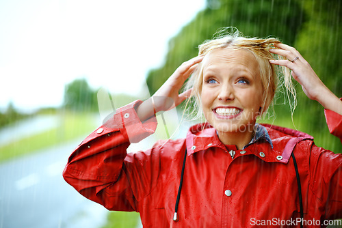 Image of Woman, smile and raincoat or hands in storm, wet and cold from weather, winter and nature. Happy female person, fashion and red jacket is trendy, rainfall and protection from water, face and playful