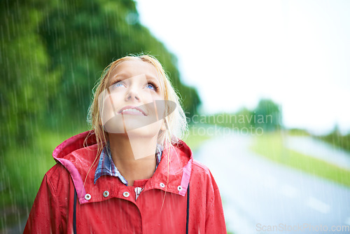 Image of Woman, smile and raincoat in outdoor rainfall, wet and cold from weather, winter and nature. Happy female person, fashion and red jacket is cool, rain and looking up to sky by water, face and holiday