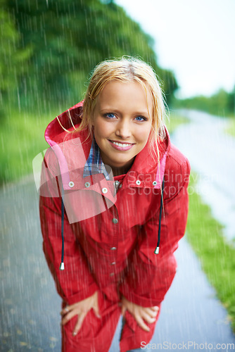 Image of Smile, portrait and young woman in the rain with coat in nature, road or street for winter. Happy, positive attitude and female person from Australia in drizzle or storm weather in outdoor forest.