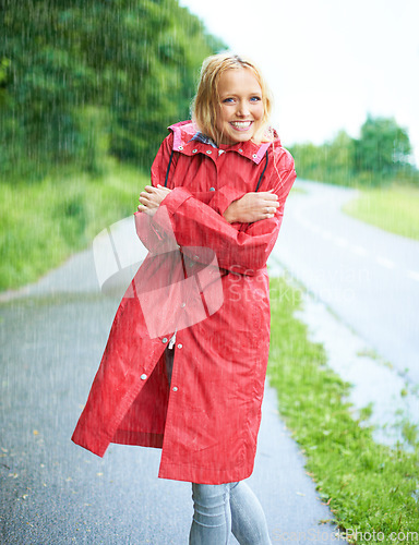 Image of Raining, portrait and young woman with coat in nature, road or street for winter in countryside. Smile, positive attitude and female person from Canada in drizzle or storm weather in outdoor forest.