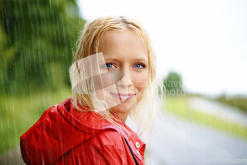 Image of Friendly, portrait and young woman in the rain with coat in nature, road or street for winter. Smile, positive attitude and female person from Australia in drizzle or storm weather in outdoor forest.