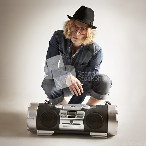 Image of Boombox, fashion and portrait of a man in retro style in studio with music, radio or sound. Male model person on a grey background with denim outfit, glasses and hipster hat listening to audio