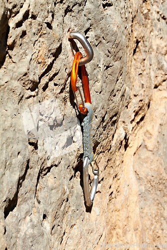 Image of Rock, climbing and carabiner tools on mountain, boulder or cliff for safety in exercise. Metal, gear and secure bolt on rocks with outdoor training and adventure in nature with danger or risk