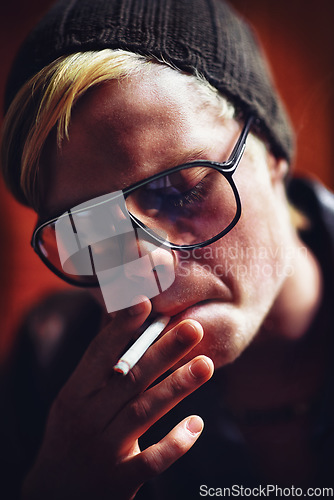 Image of Face, addiction and a boy smoking a cigarette closeup for nicotine or tobacco dependency in sunglasses. Style, smoke and bad habit with a young person inhaling an addictive substance for cancer