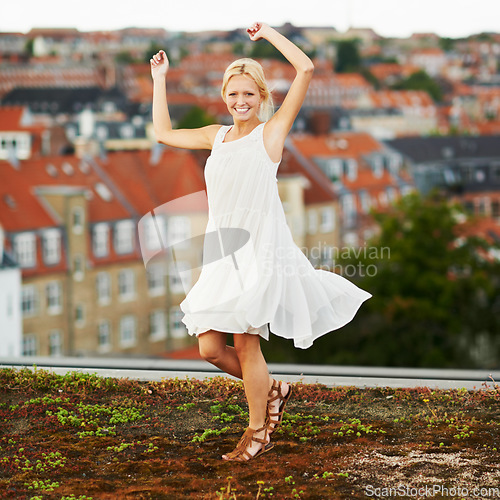 Image of Portrait, dance and smile with a woman on a roof in her neighborhood for energy or freedom in summer. Music, movement and a happy young person in celebration of her holiday or vacation as a tourist