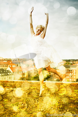 Image of Portrait, freedom and jump with a woman on a roof in the city and fun against a bokeh effect. Smile, neighborhood or arms raised and a happy young person with energy outdoor to dance in summer