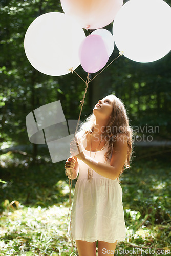 Image of Woman, holding balloons and peace in nature, playful and outdoors in forest, party decor and celebrate for freedom. Female person, sunshine and birthday in park, milestone and achievement for growth