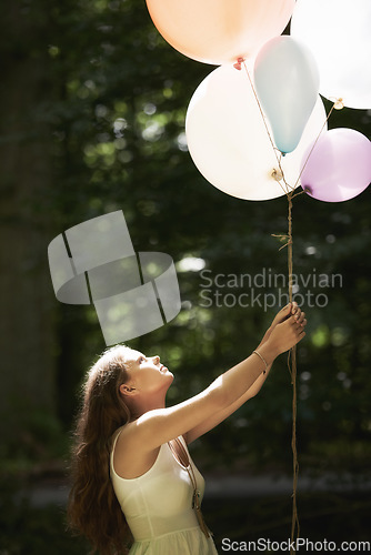 Image of Woman, holding balloons and fun in nature, playful and outdoors in forest, party decor and celebration for freedom. Female person, sunshine and birthday in park, milestone and achievement for growth