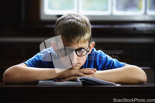 Image of Kid, school and angry on desk, book and staring for education, adhd and child development. Anxiety, stress and burnout from dyslexia, moody or mental health issue for studying, frustrated and autism