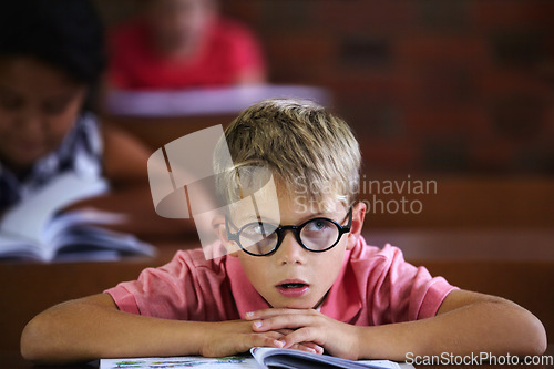 Image of Classroom, student and boy with thinking, bored and education with glasses, learning and teaching. Kid, school and child with eyewear, development, notebook or tired with a test, morning and studying