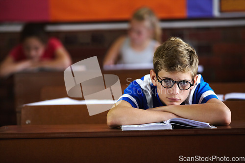 Image of Education, classroom and bored with a boy student or nerd at desk, listening to lesson for growth or development. School, book and learning with young adhd child in class to study for an exam or test