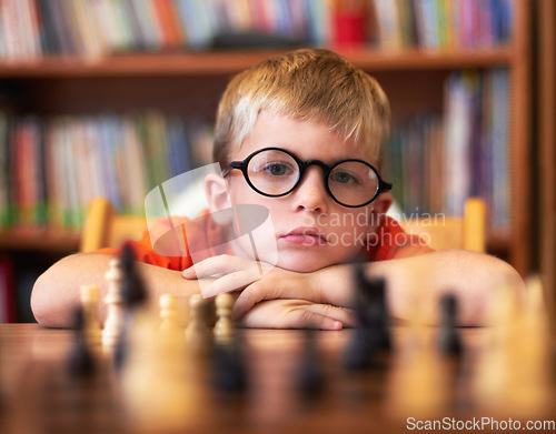 Image of Chess, thinking or bored with a boy student learning how to play a boardgame at school for education. Face, strategy and glasses with a young student child in a classroom for intelligence development