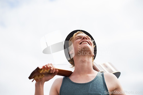 Image of Freedom, sky and man with guitar, smile and inspiration in nature for talent, journey and vacation. Artist, musician or guitarist with creative thinking, music and travel adventure with happy holiday