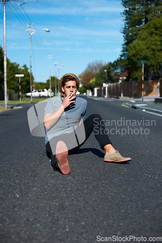 Image of Cool, man and sitting in the street for smoking, stylish and streetwear fashion. Trendy, young and a person with a cigarette for smoke, tobacco or nicotine habit in the road for youth aesthetic