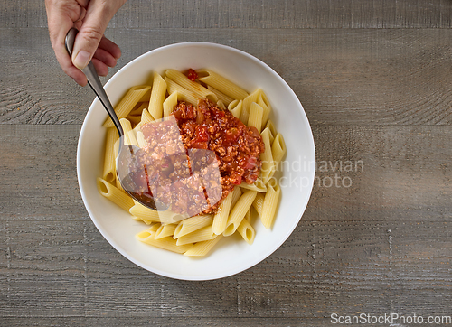 Image of bologna sauce is added to a bowl of pasta