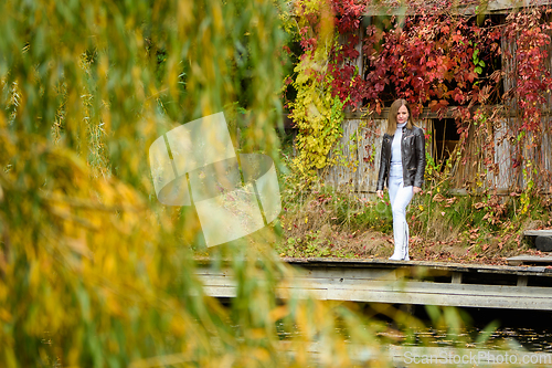 Image of A young beautiful girl walks through an old autumn park