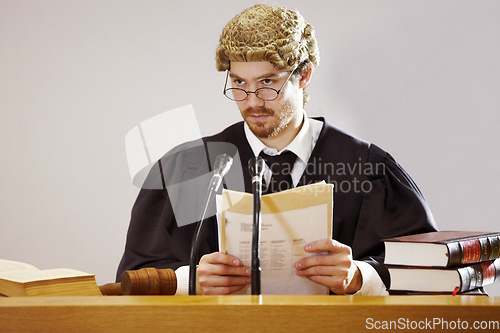 Image of Legal, documents and a judge man in court with trial evidence for a verdict to punish crime. Law, justice and glasses with a serious lord justice listening to proof or testimony for criminal sentence