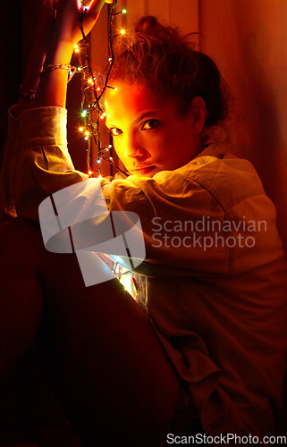 Image of Christmas lights, portrait and young woman in a room for festive decoration for the holidays. Celebration, modern and female person from Canada relaxing or chilling in a modern apartment or home.