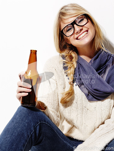 Image of Happy woman, portrait smile and relax with beer of nerd, geek or hipster against a studio background. Attractive female person or model with glasses, nerdy or fashion style holding bottle of alcohol