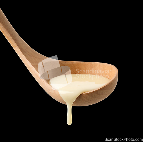 Image of condensed milk in wooden ladle