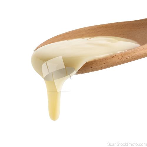 Image of condensed milk in wooden spoon