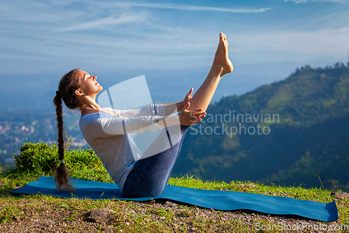 Image of Woman doing Ashtanga Vinyasa Yoga asana Navasana - boat pose