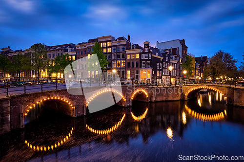 Image of Amsterdam canal, bridge and medieval houses in the evening