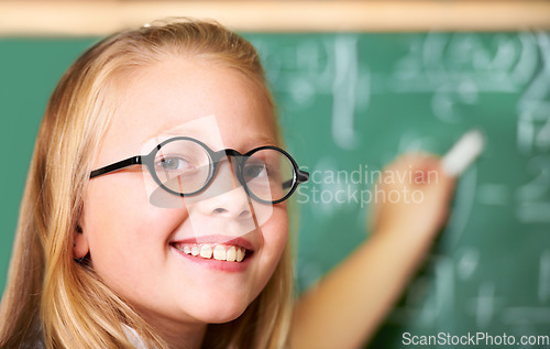 Image of Portrait, nerd and happy kid writing on chalkboard in class for learning, education and study math. Face, glasses and smile of geek at school, cute girl child and student in classroom in Australia