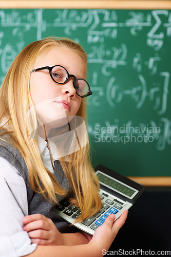 Image of Child, portrait and calculator by chalkboard for education, learning and problem solving or solution with confidence. Smart kid, student or girl with glasses for school, numbers and math in classroom
