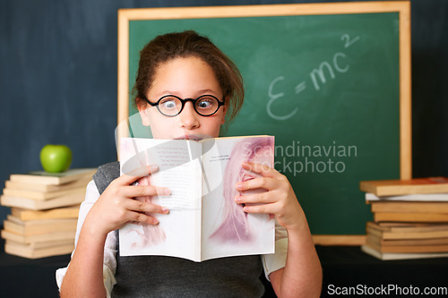 Image of Shock, reading and child student with a book in the classroom for education, learning or knowledge. Study, nerd and girl kid with glasses enjoying a story or novel with surprise face at school.