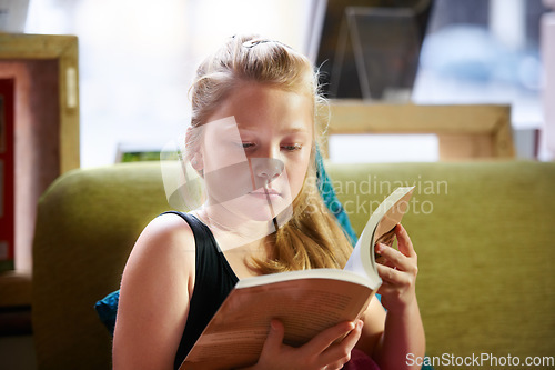 Image of Relax, reading and child student with a book in living room for education, learning or knowledge. Study, nerd and girl kid enjoying a story, fantasy or novel in the lounge at modern home or house.
