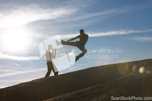 Image of Jump, kick and karate men on mountain top for fitness, training or body, speed or power on blue sky background. Martial arts, taekwondo or MMA friends workout in nature for cardio, exercise or sports