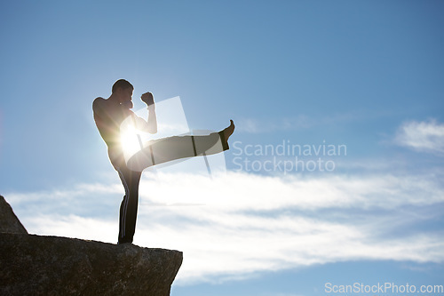 Image of Fitness, kick and karate man on mountain top for body, power or defense training on blue sky background. Martial arts, MMA and male taekwondo master in nature for exercise, sports or morning cardio