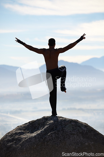 Image of Karate, balance and fitness man on mountain top for body training, power or workout on blue sky background. Martial arts, MMA and male taekwondo master in nature for exercise, sport or morning cardio