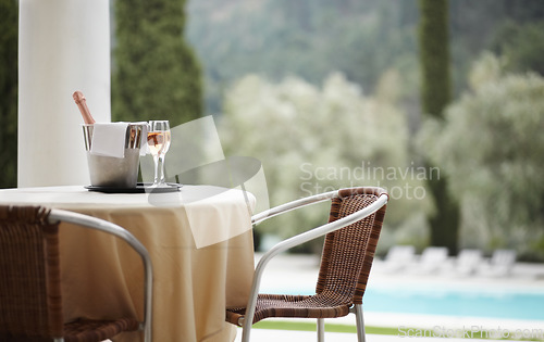 Image of Hotel, outdoor and hospitality with champagne, glass and luxury pool view for accommodation and experience. Travel, drinks and table with wine at a villa for service, vacation or romantic getaway