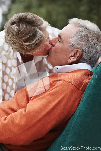 Image of Kiss, love and senior couple relax in a backyard with freedom, fun and bonding at home together. Gratitude, care and old people with passion, security or support in a yard sharing a romantic moment