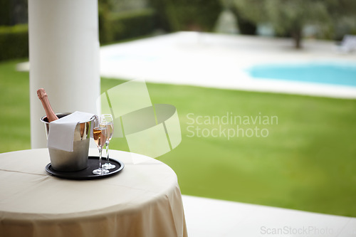 Image of Hospitality, outdoor and hotel with champagne, glass and pool view for luxury, accommodation and experience. Travel, freedom and table with wine at a villa for service, vacation or romantic getaway