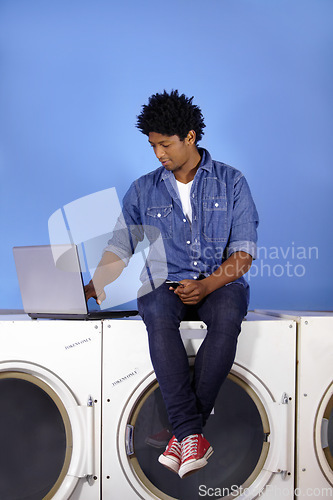 Image of Washing machine, laptop and phone of a black man for laundromat, communication and reading email. Cleaning, typing and a male employee or management of laundry room from the internet with tech
