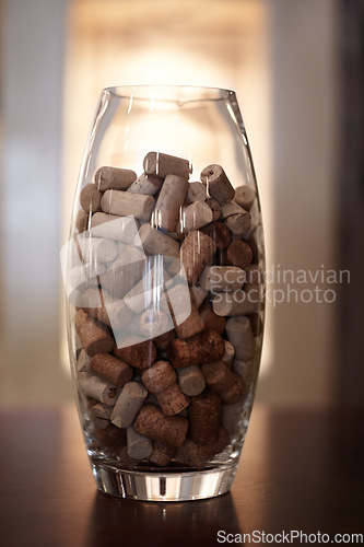 Image of Winery, glass and jar with a group of cork plugs on a wooden table closeup for decoration or preservation. Background, texture and interior design with stopper seals in a vase for sustainability