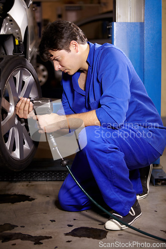 Image of Mechanic, man and change wheel in shop, electric drill and car service or auto repairs for maintenance. Technician, male person and tire safety for automobile, rim and vehicle inspection in workshop