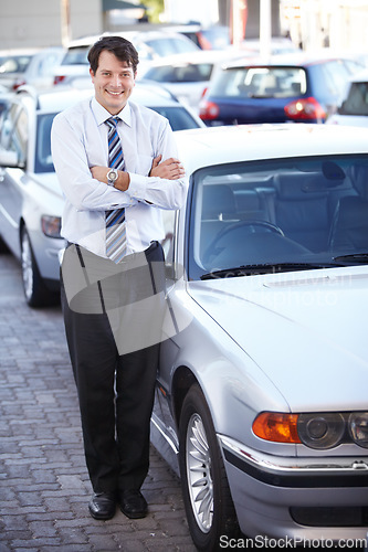 Image of Portrait, lease and a man arms crossed at a dealership for car sale in a commercial parking lot. Business, rental and automobile trade with a happy young salesman outdoor for transport service