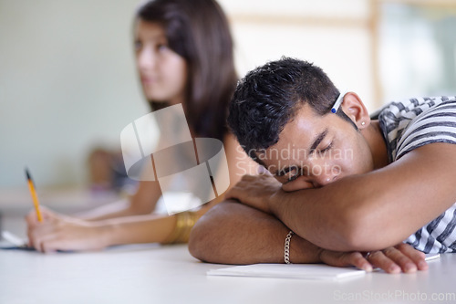 Image of Tired, sleeping and a bored man in a classroom for learning, education and university burnout. Mental health, campus and a male student at a desk for rest, stress or fatigue in a college lecture
