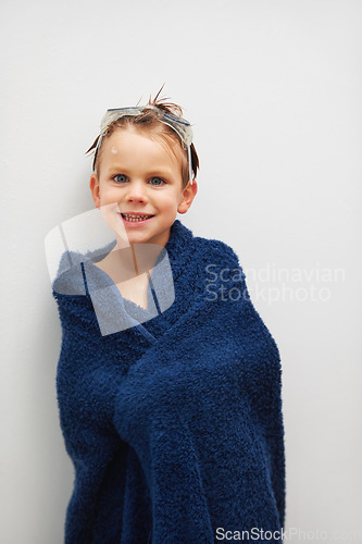 Image of Portrait, bath and a boy in a towel in studio on a white background to dry after cleaning for hygiene. Children, smile and a happy young kid in the bathroom of his home for skincare or wellness