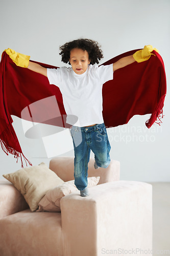 Image of Fly, children and a boy superhero in a costume on a sofa in the living room of his home for playing a game. Jumping, growth and fantasy with a young kid in a cape for justice or safety cosplay